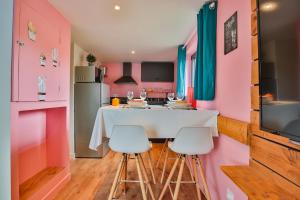 a kitchen with pink walls and a white table and chairs at CHALET CARAIBES SPA Privatif in Clermont-Créans