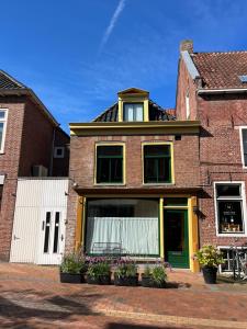 uma casa de tijolos com portas e janelas verdes em Suite van Lotte em Dokkum