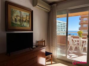 een woonkamer met een televisie en een balkon bij Bella Terraza frontal al Mar in Oropesa del Mar