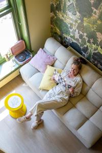 uma mulher deitada num sofá numa sala de estar em Suite van Lotte em Dokkum