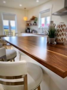 einen großen Holztisch in einer Küche mit weißen Stühlen in der Unterkunft Bambury's Hillside Chalets in Rocky Harbour