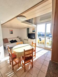 ein Wohnzimmer mit Tisch und Stühlen und ein Schlafzimmer in der Unterkunft Appartement coup de coeur les pieds dans l'eau in Le Barcarès