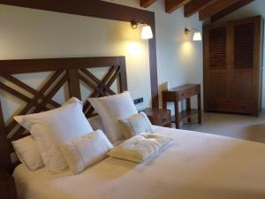 um quarto com uma grande cama branca com almofadas brancas em Les Flors - Hotel Rural & Cabanyes em Gramós
