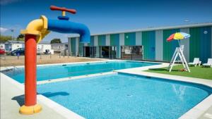 une piscine avec toboggan en face d'un bâtiment dans l'établissement 8 Birth Mobile Luxury home C016 8SG St Osyth near Clacton on Sea, à Clacton-on-Sea