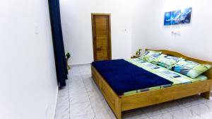 sypialnia z drewnianym łóżkiem z niebieską pościelą i poduszkami w obiekcie MILYREX VILLA 