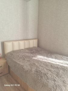 1 dormitorio con 1 cama con edredón gris en Apartment, en Tiflis