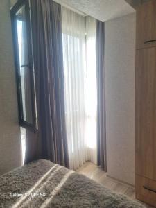 1 dormitorio con 1 cama y una ventana con cortinas en Apartment, en Tiflis