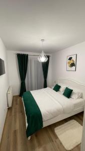 a bedroom with a large white bed with green accents at Alexia Flat in Sibiu