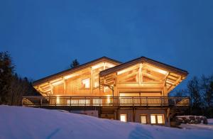 una grande casa in legno con una terrazza nella neve di Coco Chalet ad Arâches
