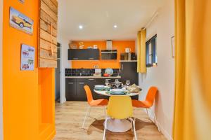 a kitchen with orange walls and a table and chairs at CHALET VINTAGE - Les Belles Ouvrières in Clermont-Créans