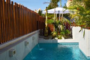 a swimming pool next to a wooden fence with a swimming pool at Alaïa Apartamentos in Playa Paraiso