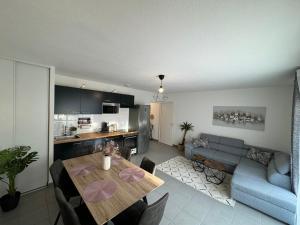 Il comprend une cuisine et un salon avec une table et un canapé. dans l'établissement Cosy Appart T3 au pied du métro et commerces, à Toulouse