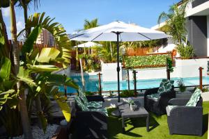 a patio with chairs and an umbrella and a pool at Alaïa Apartamentos in Playa Paraiso