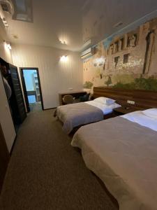 a hotel room with three beds in a row at Status Hotel in Poltava