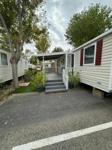 a white mobile home with a porch and stairs at MH TIKE - 4p - Les Sables du Midi - Valras in Valras-Plage