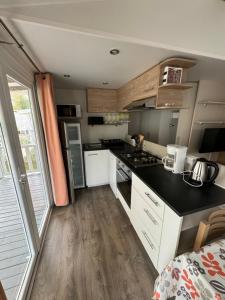 a kitchen with white cabinets and a black counter top at MH TIKE - 4p - Les Sables du Midi - Valras in Valras-Plage +11 photos