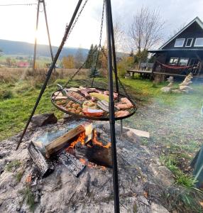 - un grill avec un bouquet de nourriture au-dessus d'un feu dans l'établissement Domek z widokiem na góry Lasówka, à Bystrzyca Kłodzka