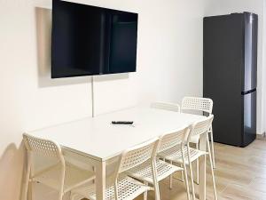 a white table and chairs with a television on a wall at T&K Apartments - Wegberg - 3-6 Zimmer Apartments in Wegberg
