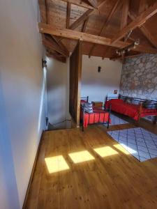 uma sala de estar com um sofá vermelho e pisos em madeira em Τα πέτρινα στο Σκεπαστό em Kalavrita