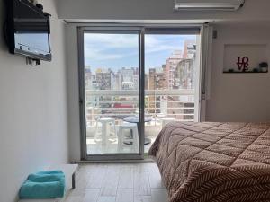 1 dormitorio con cama y ventana grande con vistas en Estudio en Barrio Martin Rosario en Rosario