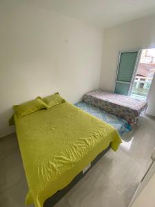 a bedroom with a yellow bed and a window at Casa de Praia - Distância de 100 metros in Praia Grande