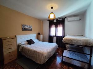 1 dormitorio con 2 camas, vestidor y ventana en A 15' Granada, Piscina, Habitaciones Familiares, Futbolín, Casa Medina Güevéjar, en Güevéjar