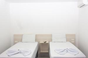 two beds in a room with white walls at Hotel Grandville II in Palmeira dos Índios