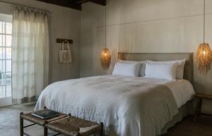 a bedroom with a large white bed and a window at Kokos Huis in Riebeek-Kasteel