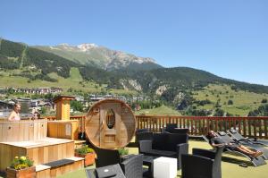 a balcony with people sitting in chairs on a deck at ALPINA LODGE VANOISE ex hotel du soleil in Aussois