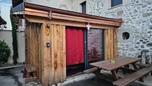 a wooden shed with a picnic table in front of a building at Spa dans les Alpes in Desingy