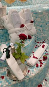 un tavolo ricoperto di asciugamani e un vaso con una rosa di Eveline 2 - Piscina Privata o Jacuzzi a Sanremo