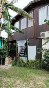 a house with glass doors and a palm tree at Casas Paz e Amor Praia do Rosa Sunset e Sunrise in Imbituba +10 photos