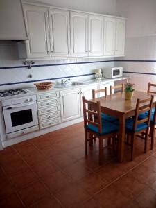 a kitchen with white cabinets and a wooden table and chairs at Quinta Marvão in Ribamar
