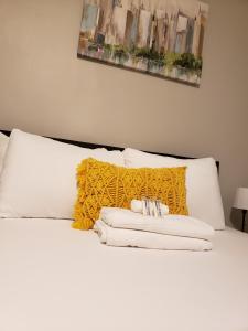 Cama blanca con manta amarilla y almohadas blancas en The City-Side at Silver Lake *NEW 1-BED RM APT en Providence