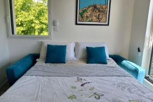 ein blaues Bett mit blauen Kissen in einem Zimmer in der Unterkunft Villa d'architecte tout près d'Honfleur - SPA in Équemauville