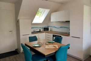 eine Küche mit einem Holztisch und blauen Stühlen in der Unterkunft Villa d'architecte tout près d'Honfleur - SPA in Équemauville