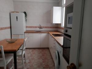 ラスパルマス・デ・グランカナリアにあるAmplio apartamento a 50 metros de la Playaのキッチン(テーブル、白い冷蔵庫付)