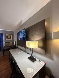 Pokój z biurkiem z lampką i telewizorem w obiekcie Rodeway Inn w mieście Emporia