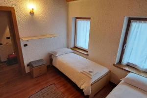 um pequeno quarto com 2 camas e 2 janelas em In cima alla contrada em Pieve di Cadore