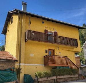Una casa amarilla con un balcón en el lateral. en In cima alla contrada en Pieve di Cadore