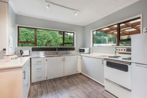 a kitchen with white cabinets and two windows at Home In Naseby in Naseby