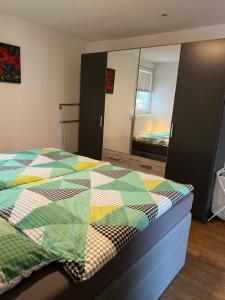 2 Zi-Apartment Fauser Echterdingen-Messe في لاينفيلدن-إشتردينغن: غرفة نوم مع سرير ولحاف ملون عليها