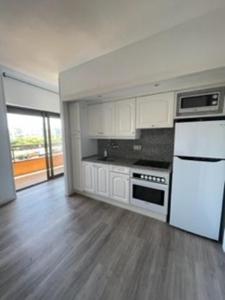 a kitchen with white cabinets and a white refrigerator at Apartamento céntrico Playa de Aro con piscina. in Platja  d'Aro