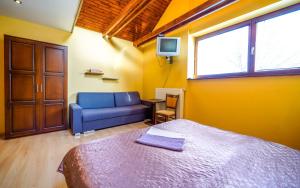 a bedroom with a bed and a couch and a tv at Studio Troika in Pavčina Lehota