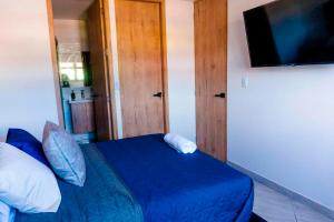 Schlafzimmer mit einem blauen Bett und einem Flachbild-TV in der Unterkunft Apartamento 402 - Terraza con Jacuzzi - 3 Habitaciones - Rentas Cortas Gerencial in Guatapé