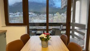 a table with a vase of flowers on it with a view at Busteni Mountain View Suites by the River - EV Plug in Buşteni