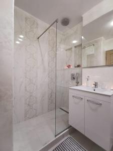トゥルグ・オクナにあるApartament Gold Luxuryのシャワーと洗面台を備えた白いバスルーム