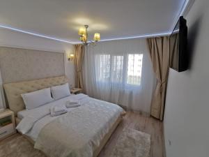 トゥルグ・オクナにあるApartament Gold Luxuryの白いシーツと窓のあるベッドのある寝室