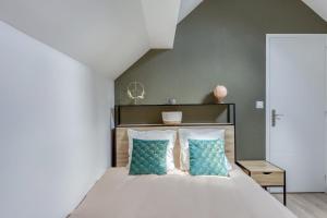 a bedroom with a large bed with blue pillows at Joli Appartement de vacances in Écouen