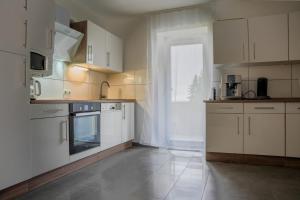a kitchen with white cabinets and a large window at Ferienwohnung AnnA in Gries